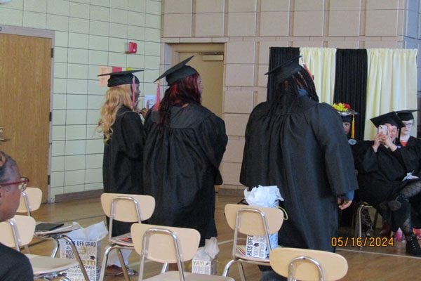 Adults in black graduation caps and gowns.